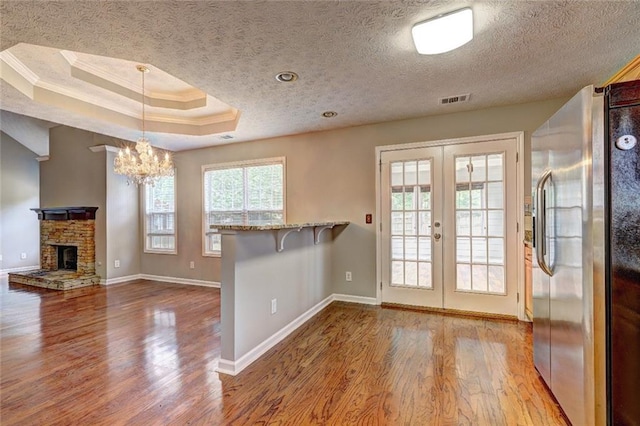 interior space with crown molding, wood finished floors, french doors, and stainless steel fridge with ice dispenser