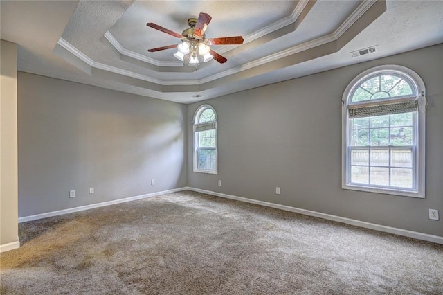 carpeted spare room with visible vents, a ceiling fan, a raised ceiling, and ornamental molding