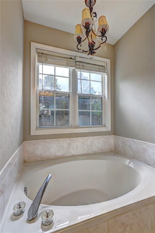 full bath featuring a bath and a notable chandelier