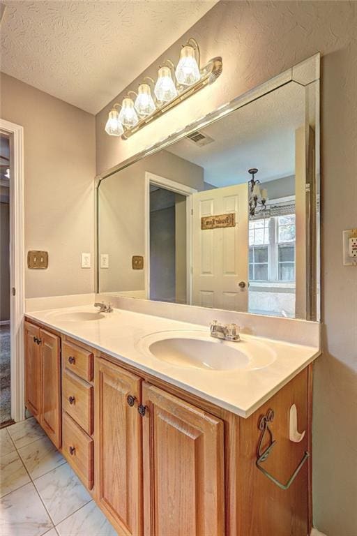 bathroom featuring double vanity, a textured ceiling, visible vents, a sink, and marble finish floor