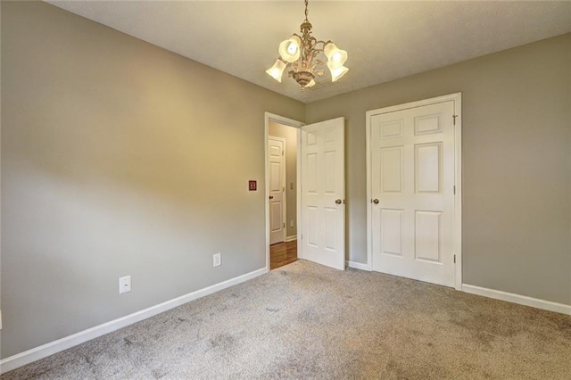 unfurnished bedroom with baseboards, a chandelier, and carpet