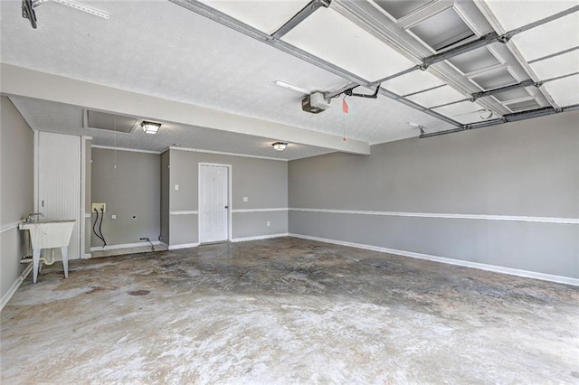 garage featuring a sink, baseboards, and a garage door opener
