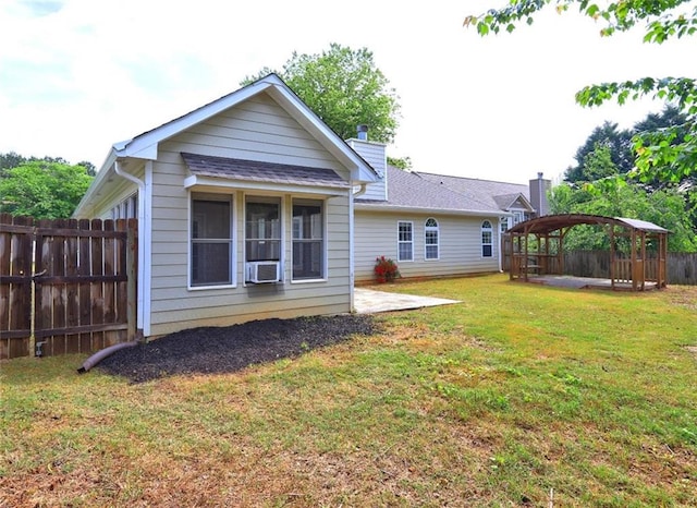 back of property with fence, a gazebo, a chimney, a patio area, and a yard