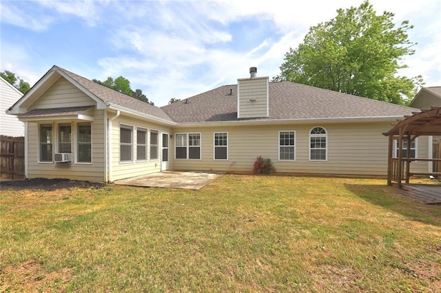 rear view of house with fence, roof with shingles, a chimney, a patio area, and a lawn
