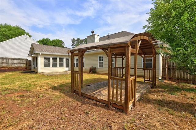 rear view of house with a gazebo, a fenced backyard, a yard, and a chimney