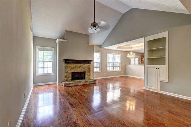 unfurnished living room featuring baseboards, ceiling fan with notable chandelier, and a wealth of natural light