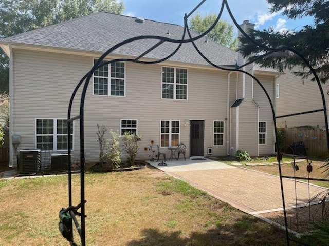 rear view of property with a lawn, a patio, and central air condition unit