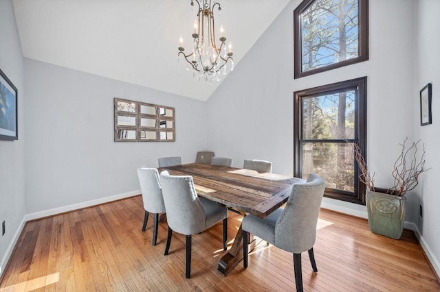 dining area featuring light hardwood / wood-style flooring, high vaulted ceiling, and a chandelier