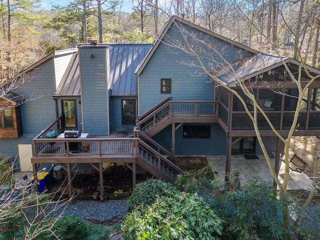 back of property featuring a wooden deck, a sunroom, and a patio