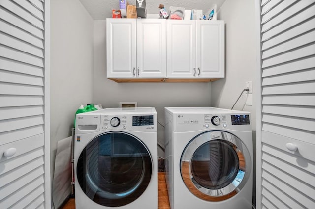 clothes washing area with cabinets and washing machine and clothes dryer