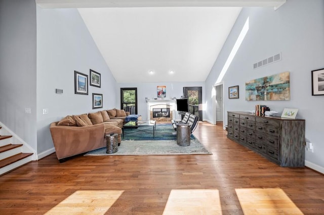 living room featuring high vaulted ceiling and light hardwood / wood-style floors