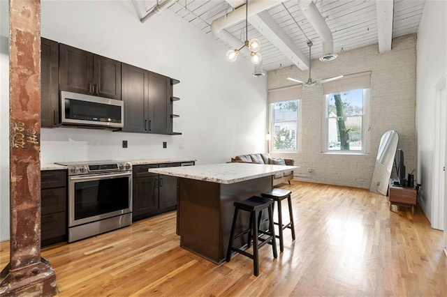 210 Walker St SW Unit 3, Atlanta, GA 30313 - kitchen with appliances with stainless steel finishes, brick wall, open shelves, dark brown cabinets, and a breakfast bar