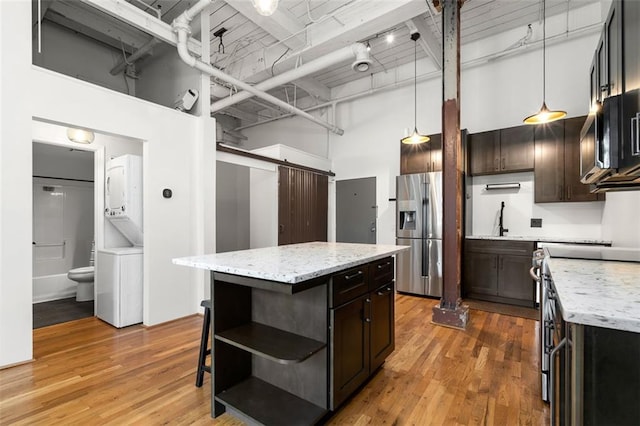 210 Walker St SW Unit 3, Atlanta, GA 30313 - kitchen with estacked washer and dryer, appliances with stainless steel finishes, open shelves, a high ceiling, and light wood-type flooring