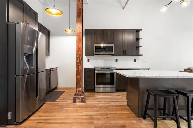 210 Walker St SW Unit 3, Atlanta, GA 30313 - kitchen featuring stainless steel appliances, open shelves, light wood-style flooring, a breakfast bar area, and dark brown cabinets