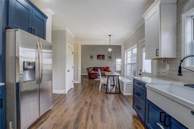 kitchen with ornamental molding, light countertops, blue cabinetry, and stainless steel refrigerator with ice dispenser