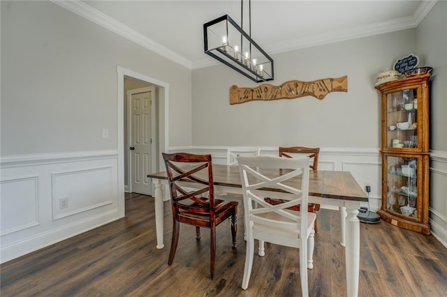 dining space featuring a notable chandelier, dark wood-style flooring, wainscoting, and crown molding