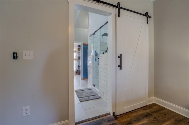 hall featuring dark wood-style floors, a barn door, and baseboards