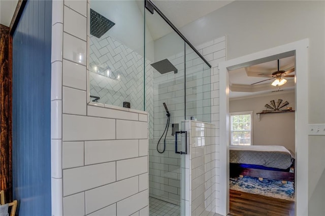 ensuite bathroom featuring a raised ceiling, ensuite bath, ceiling fan, wood finished floors, and a shower stall