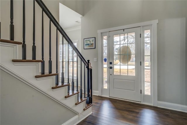 foyer entrance featuring dark wood-type flooring, crown molding, baseboards, and stairs