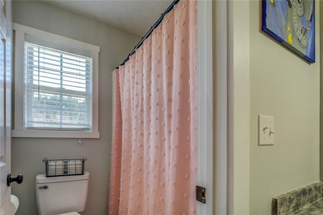 full bath featuring a textured ceiling and toilet