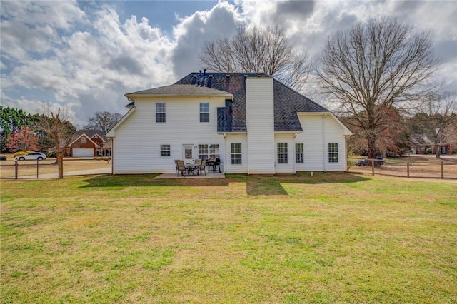 back of house with a patio area, a chimney, fence, and a lawn