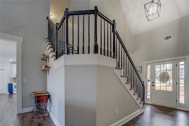 entryway with visible vents, a towering ceiling, baseboards, and wood finished floors