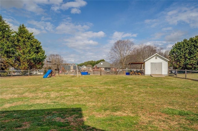 view of yard with a storage shed, a fenced backyard, a playground, and an outbuilding