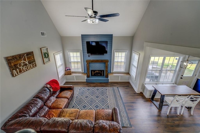 living room with dark wood finished floors, visible vents, a large fireplace, ceiling fan, and high vaulted ceiling