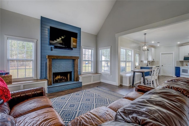 living area with a healthy amount of sunlight, a large fireplace, wood finished floors, and lofted ceiling