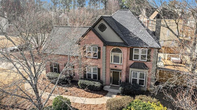 view of front of home with roof with shingles and brick siding