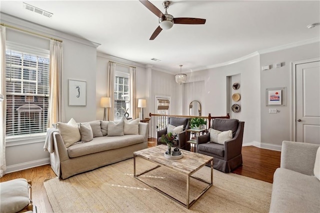 living room with visible vents, crown molding, light wood-style flooring, and baseboards