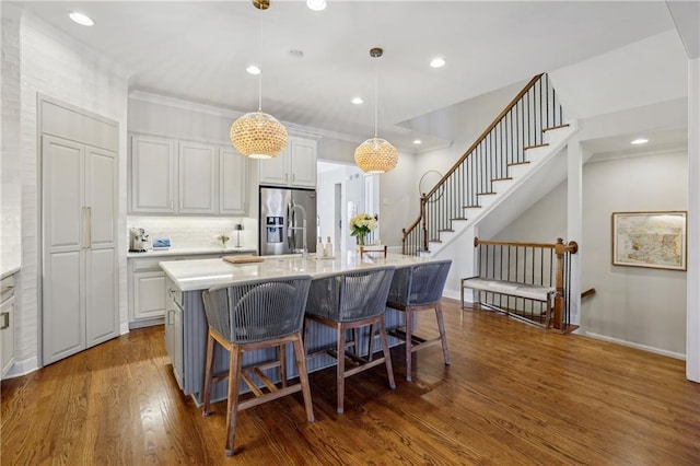 kitchen featuring dark wood-style floors, a breakfast bar, light countertops, and stainless steel fridge with ice dispenser