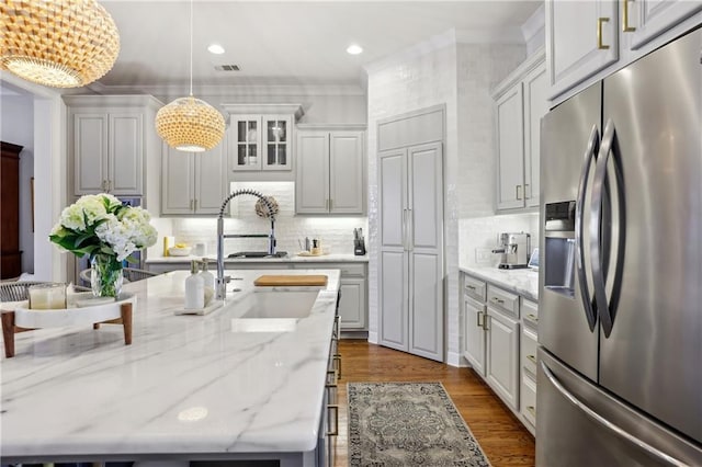 kitchen with dark wood-style flooring, decorative light fixtures, visible vents, backsplash, and stainless steel fridge