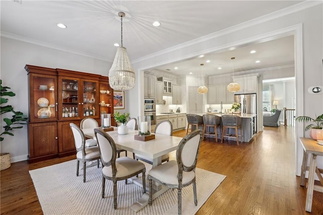 dining space with recessed lighting, an inviting chandelier, ornamental molding, wood finished floors, and baseboards