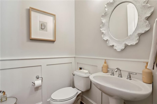 bathroom featuring a wainscoted wall, a sink, and toilet