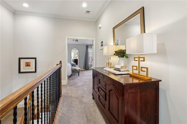 hallway featuring arched walkways, light colored carpet, an upstairs landing, visible vents, and ornamental molding