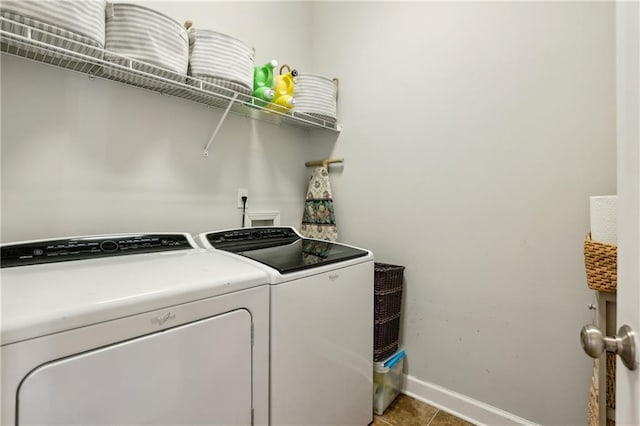 washroom featuring light tile patterned floors, laundry area, washing machine and clothes dryer, and baseboards