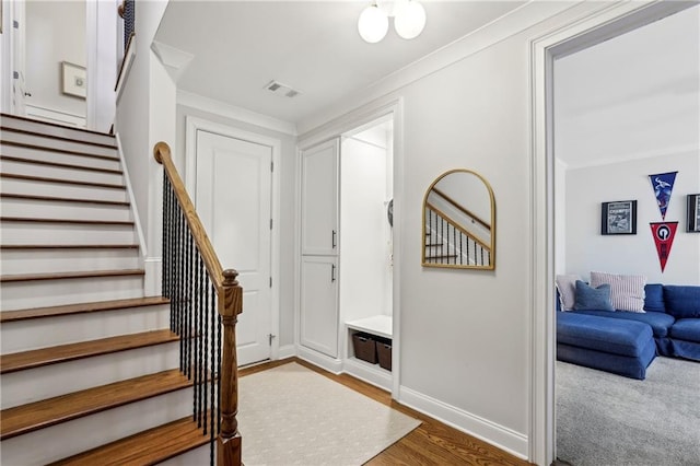 foyer entrance featuring baseboards, stairs, visible vents, and crown molding