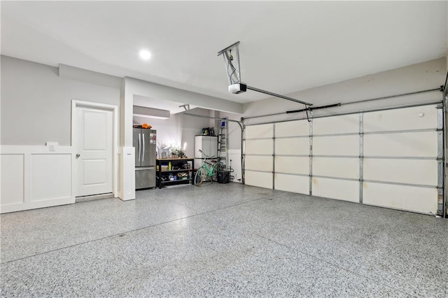 garage with a garage door opener and freestanding refrigerator