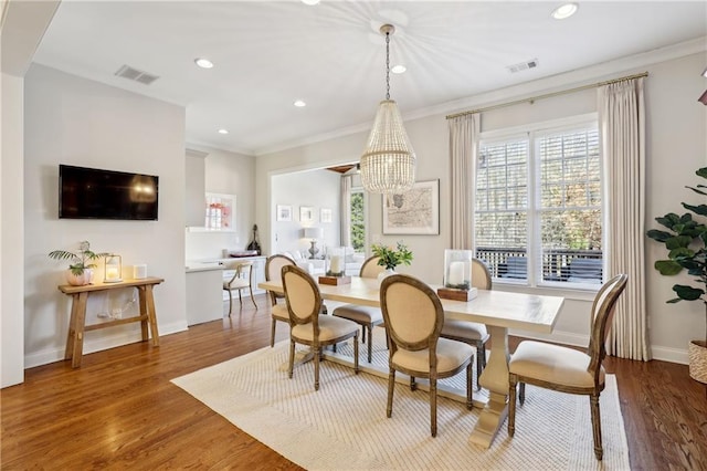 dining room with baseboards, visible vents, wood finished floors, crown molding, and recessed lighting