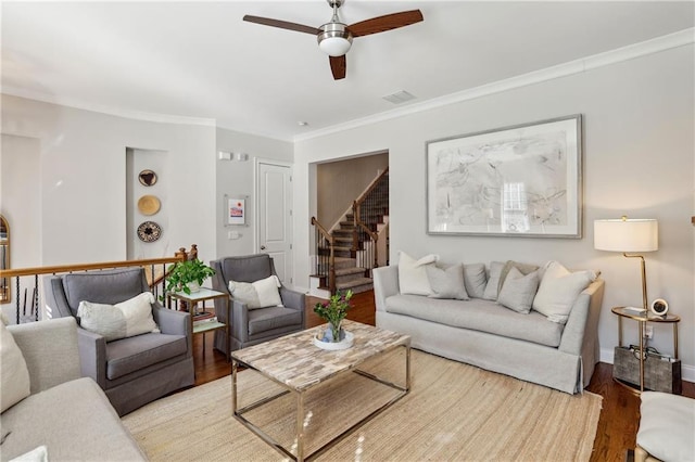 living room featuring visible vents, a ceiling fan, stairway, ornamental molding, and wood finished floors