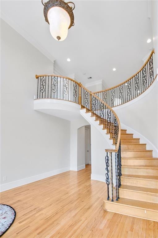 staircase with a towering ceiling and hardwood / wood-style floors