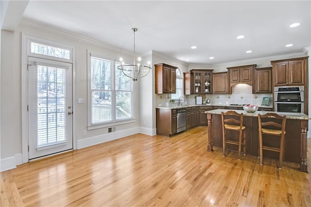 kitchen featuring sink, appliances with stainless steel finishes, a kitchen breakfast bar, a kitchen island, and light stone countertops