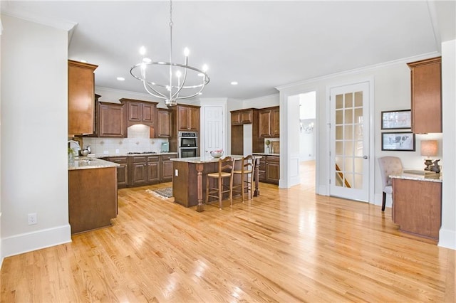 kitchen featuring a breakfast bar, backsplash, light hardwood / wood-style floors, a kitchen island, and a chandelier