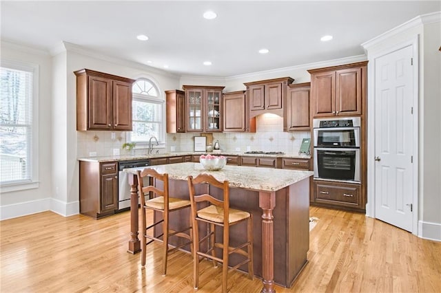 kitchen with a breakfast bar, sink, light stone counters, a kitchen island, and stainless steel appliances