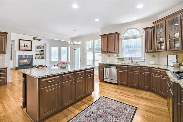 kitchen featuring sink, dark brown cabinets, hanging light fixtures, stainless steel dishwasher, and light hardwood / wood-style floors