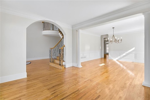 unfurnished living room with crown molding, an inviting chandelier, and light hardwood / wood-style floors