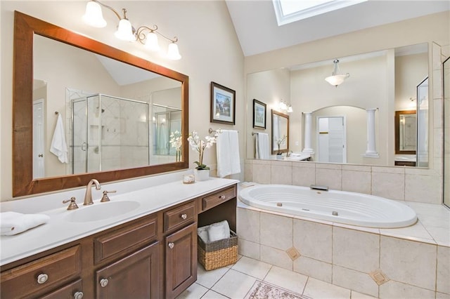 bathroom with tile patterned flooring, lofted ceiling with skylight, vanity, and decorative columns