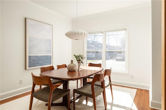 dining room with light wood-style flooring, baseboards, and ornamental molding