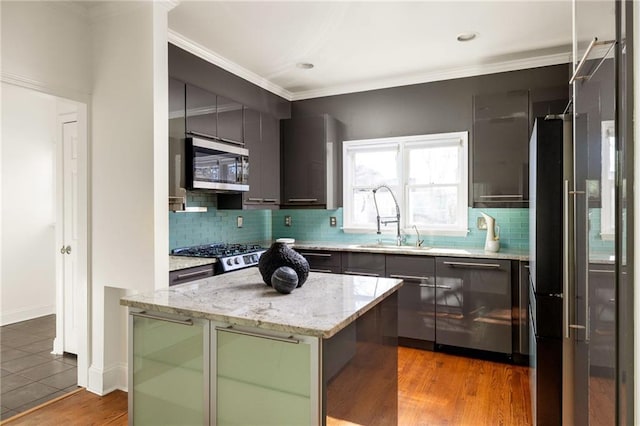 kitchen with light wood-style flooring, a sink, appliances with stainless steel finishes, tasteful backsplash, and crown molding